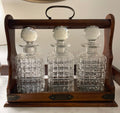 set of three antique crystal decanters in an oak Tantalus